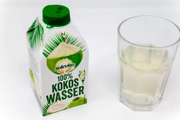 100% coconut water in a beverage carton next to a filled glas