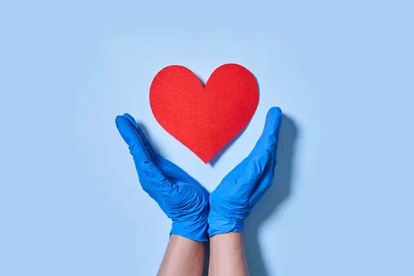 13. Doctor hands hold red heart over blue background