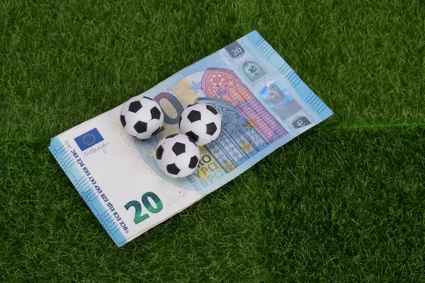 20 Euro banknote with soccer balls on green grass