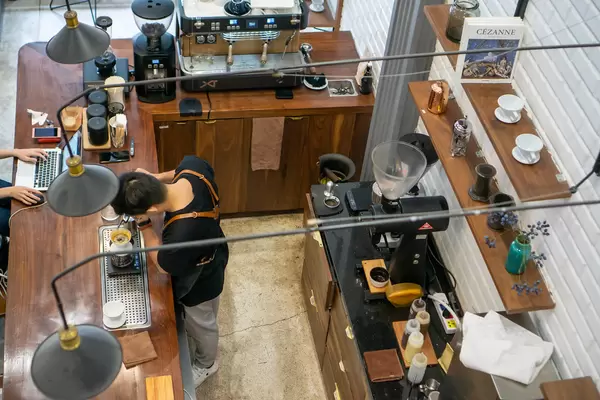 A Barista Pouring Hot Water in a Coffee Filter making Dripping Coffee in a modern Cafe in Vietnam