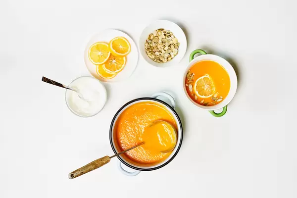 A beautiful arrangement of dishes with fresh homemade vegetable cream soup, lemon slices and pumpkin seeds