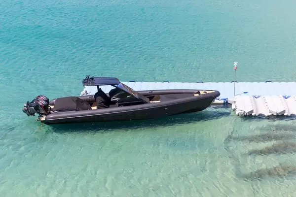 A black motor boat at a pier in the crystal-clear waters of Kalo Livadi, Mykonos