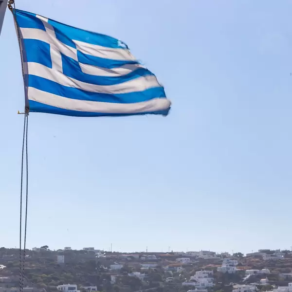 A blue and white Greek flag in the wind against the sky on the island of Mykonos