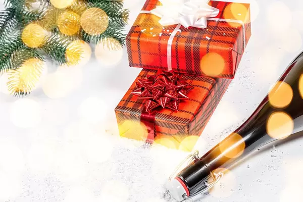 A bottle of champagne and Packed gifts on the background of snow, bokeh with branches of the Christmas tree (Flip 2019)