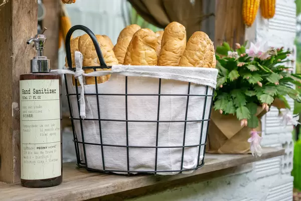A Bottle of Hand Sanitizer next to a Basket with Baguettes