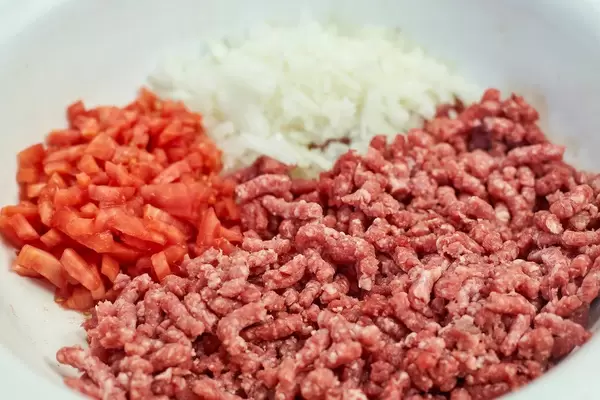 A bowl full with stuffed meat, onion and tomatoes, ready for dinner preparation