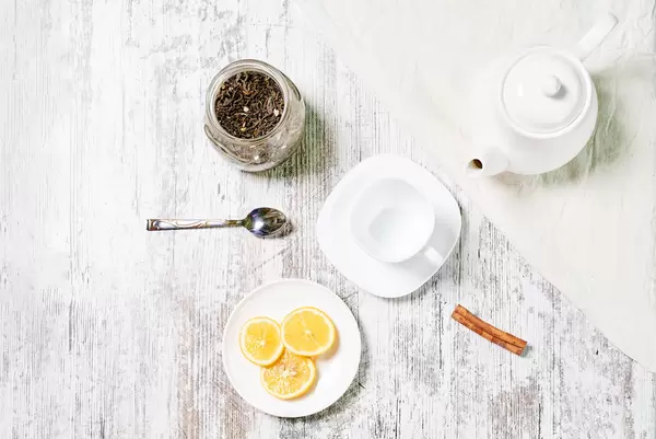 A bowl of dry tea, lemon slices and a pot of hot water for making healthy tea