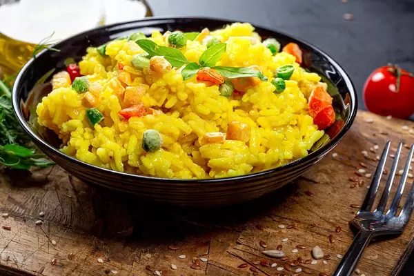 A bowl of rice and vegetables on an old kitchen board