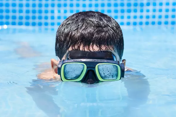 A boy in diving mask having fun in the swimming pool