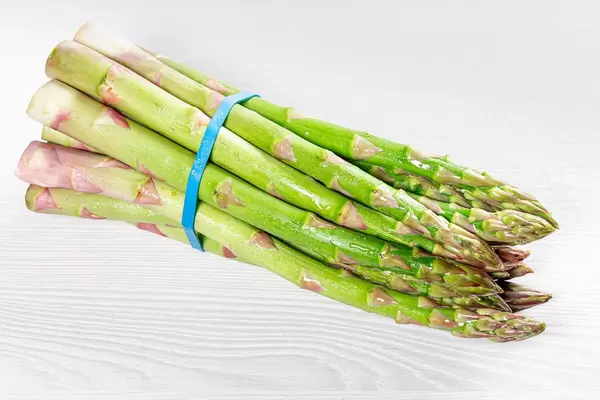 A bunch of fresh asparagus on a white wooden table (Flip 2019)