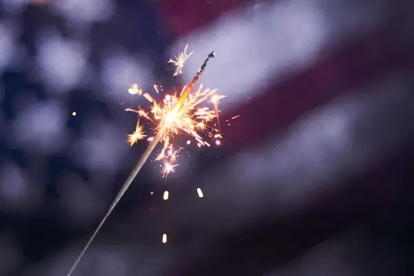 A burning sparkler over the American flag. Celebrating US Independence day, Memorial day or Flag day