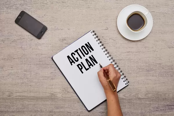 A business person writing action plan on notepad