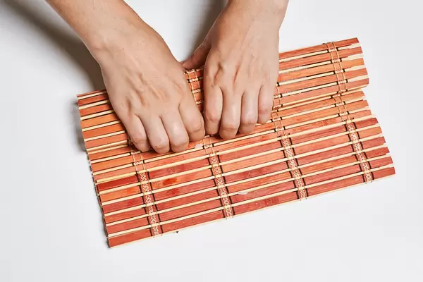 A chef turns nori sheet with filling