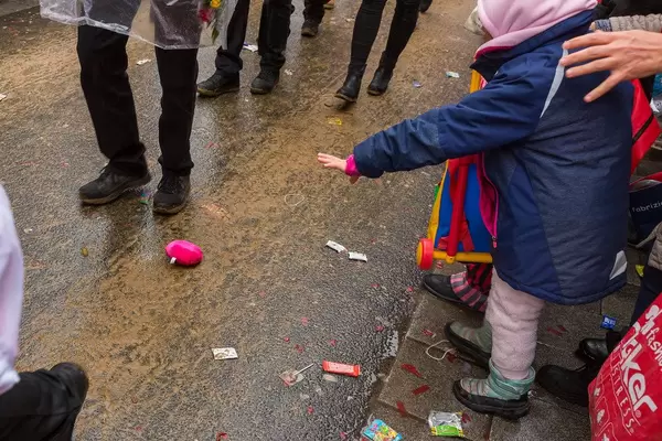 A child attending the Rose Monday parade at the Cologne carnival reaches her hand out to collect gifts thrown from the floats