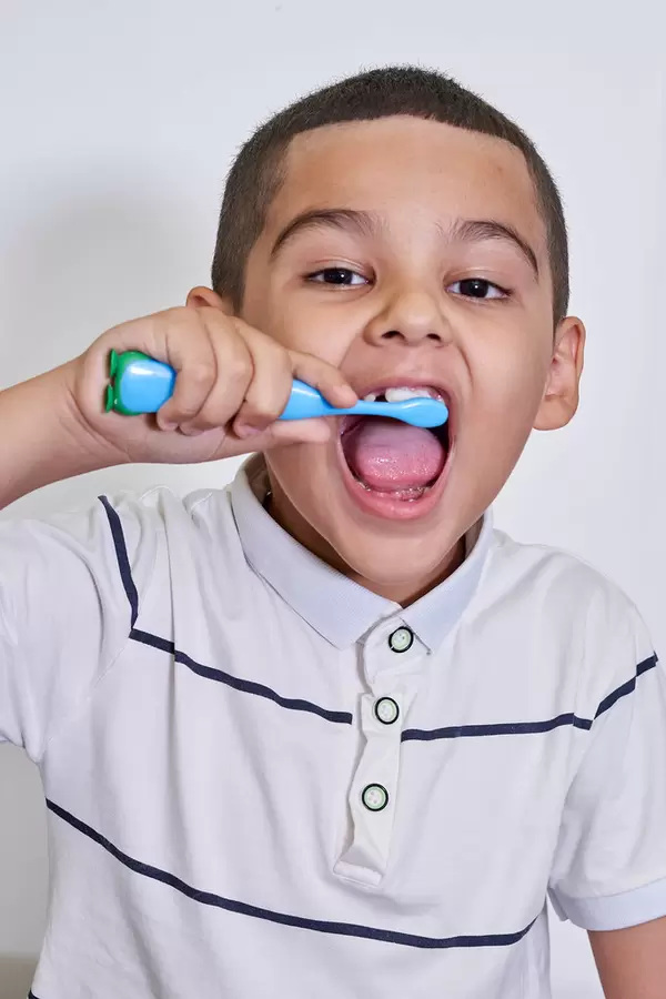 A child with funny face brushing his teeth before going to bed