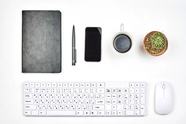 A content manager workspace with pc keyboard, leather notepad, smartphone and coffee cup on white