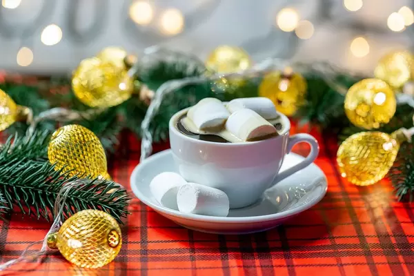 A Cup of coffee with marshmallows and garland on a Christmas background