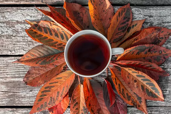 A Cup of tea with autumn leaves on an old wooden background. The view from the top (Flip 2019)