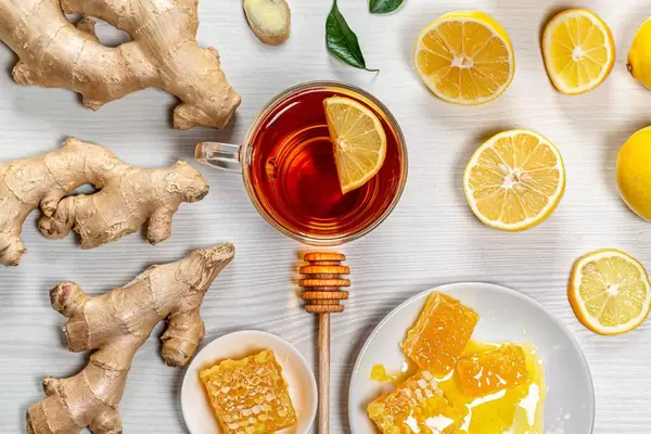 A Cup of tea with ginger root, fresh lemon and honey on a white wooden background. The view from the top