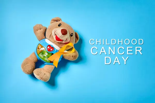 A cute children's toy with a pinned yellow ribbon on blue background