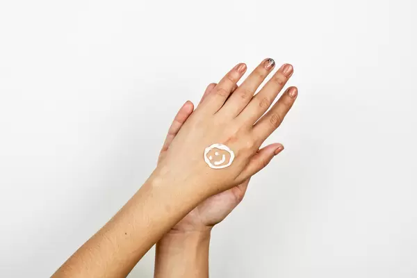 A cute smile made with cosmetic cream on cute female hands