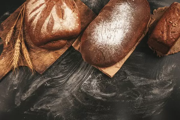 A delicious freshly baked rye bread ruddy on dark background, top view