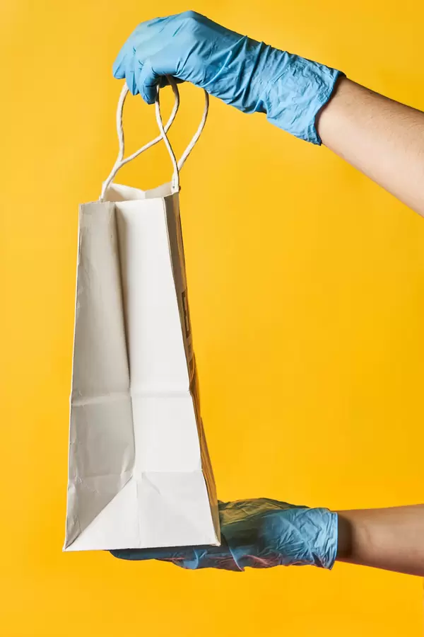A deliveryman in protective gloves brings ordered clothes from the online shop