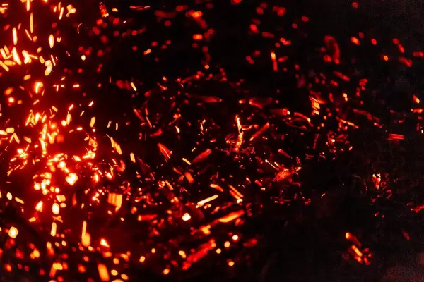 A dying fire with sparks and coals at night