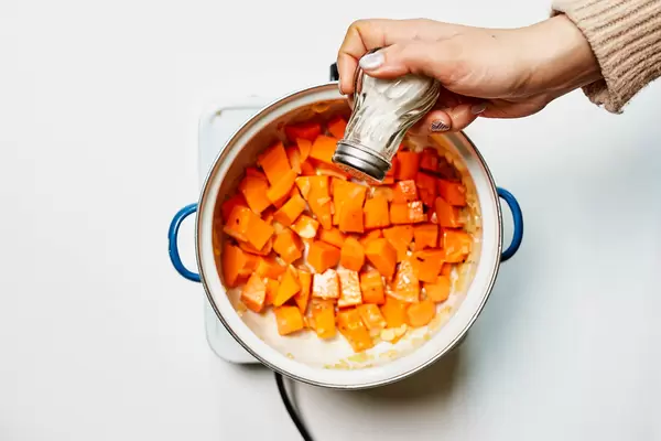 A female salting pumpkin soup