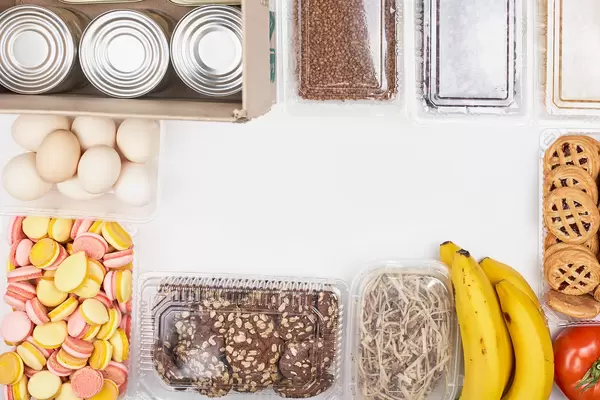 A frame of food donations with copy space in the middle: eggs, bananas, sweets, tin cans, tomatoes