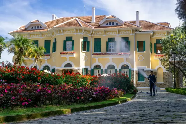 A Gardener Watering Flowers and Plants of a Garden in front of Bao Dai King Palace in Da Lat, Vietnam