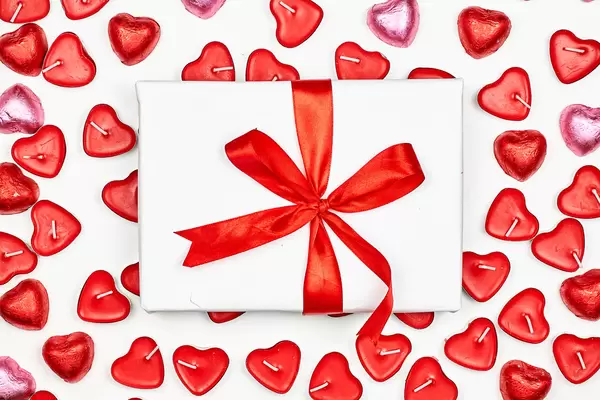 A giftbox over the heart-shaped candles on white