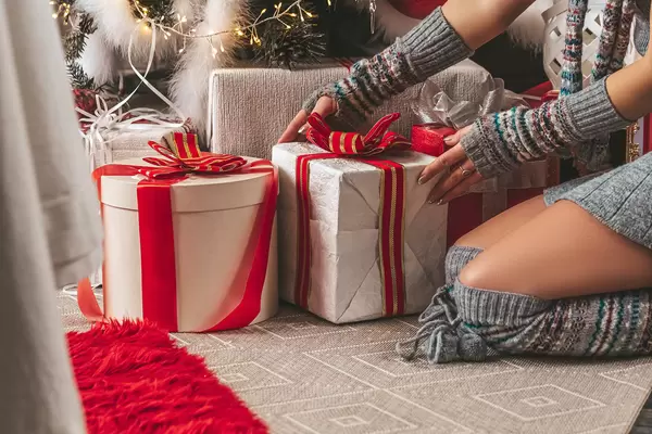 A girl lays out gifts under a christmas tree