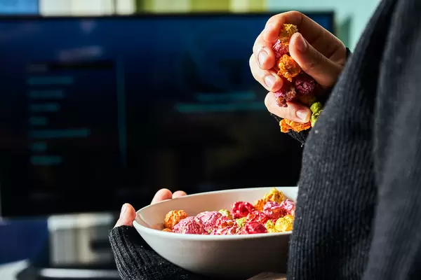 A girl watching TV and eating popcorn