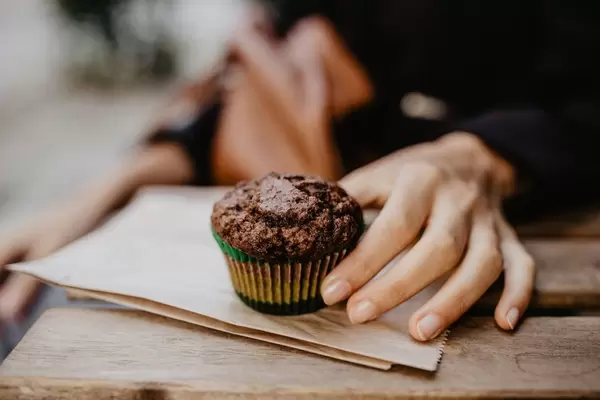 A girl's hand holding a chocolate cupcake.
