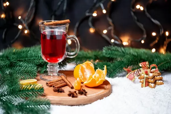 A glas of mulled wine with tangerines, cinnamon and christmastree branches on round cutting board