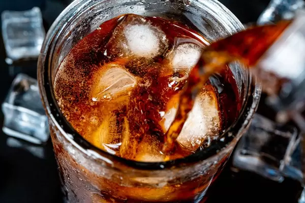 A glass of cold Pepsi with ice on a dark background