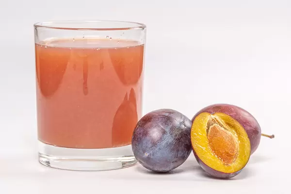 A glass of fresh plum juice with fresh ripe plums