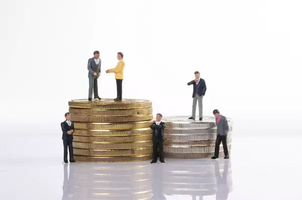 A group of miniature businessman on stack of coins closeup