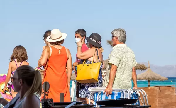 A group of tourists in Mallorca in summer 2020, some wearing a face mask against Covid-19 infection