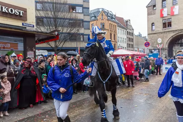 A horse rider of the Blaue Funken, traditional carnival society of Cologne, is accompanied during the Rose Monday Parade at Severinstorburg