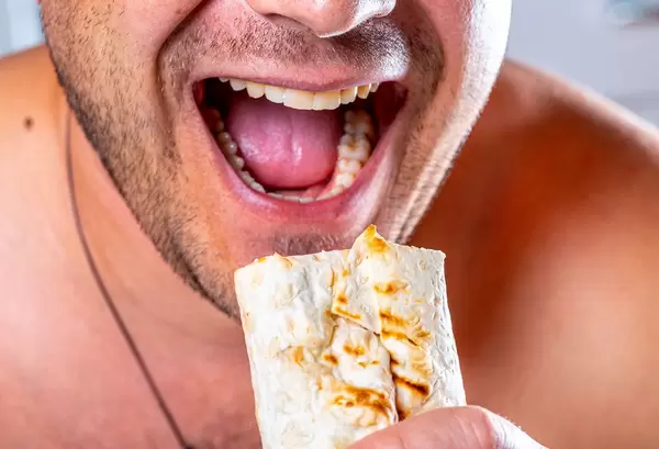 A hungry man with an open mouth and a shawarma in hand (Flip 2019)