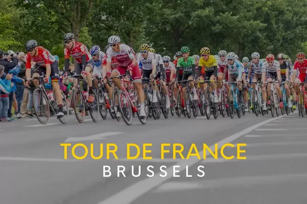 A large group of cyclists at the world famous cycling race, next to the text "Tour de France Brussels".