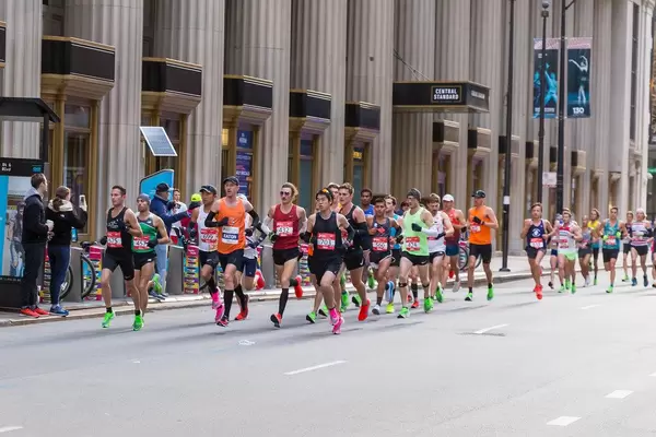 A large group of male athletes running past the Central Standard Building in Chicago's Central Loop during the Chicago Marathon 2019