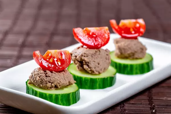 A light snack with cucumbers, liver pate and slices of cherry tomatoes