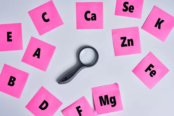 A magnifying glass among sticky notes with various vitamins
