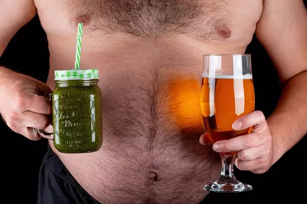 A man holds a glass of beer and a jar of green smoothies. Concept of choice