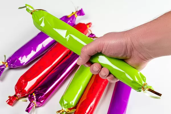 A man holds a large candy in his hand, close-up