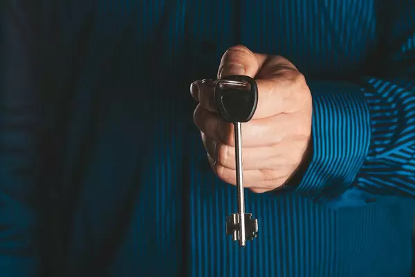 A man in a blue shirt holds a key in his hand