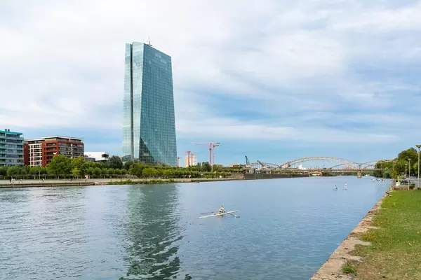 A man rowing in canoe in front of the modern building of European Central Bank